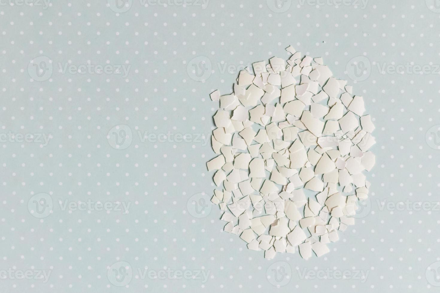 Pieces of white shell chicken egg, folded in the shape of an egg on a blue background, easter patter photo