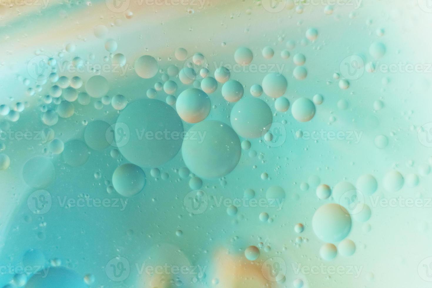 Fotografía macro de gotas de aceite en el agua sobre un fondo borroso azul verde foto