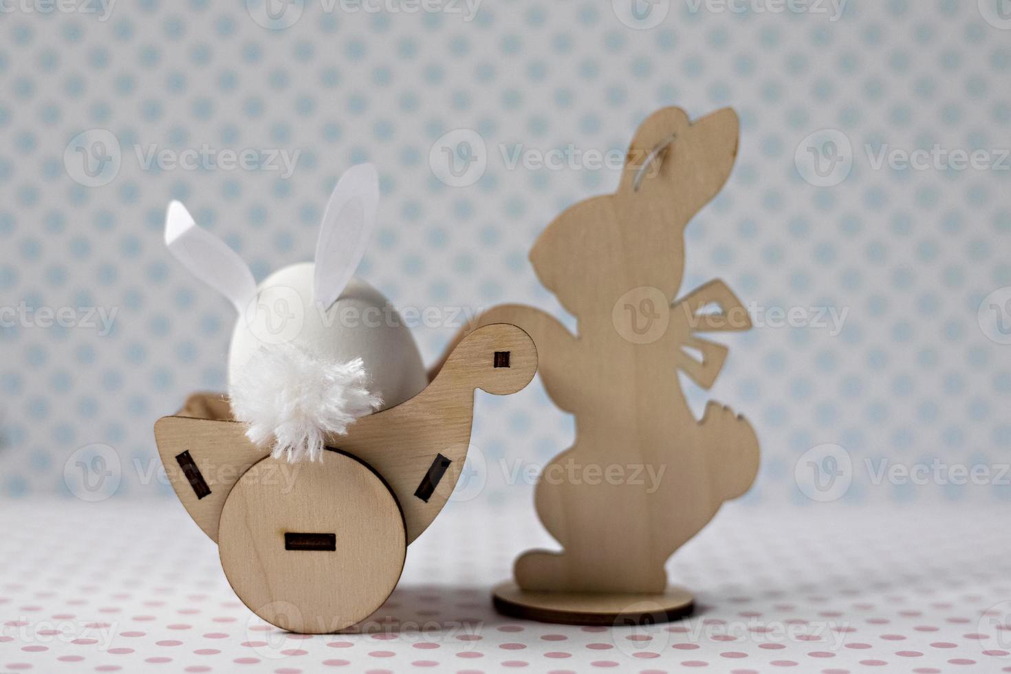 A wooden rabbit carries a cart with an egg with bunny ears. Easter decorations photo