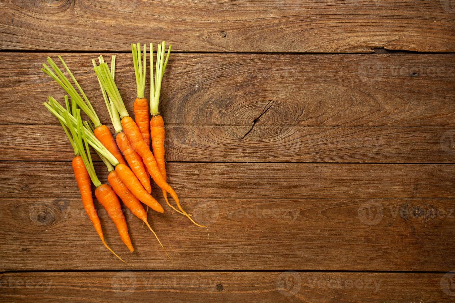 zanahorias frescas frescas sobre tabla de cortar de madera y fondo de madera foto