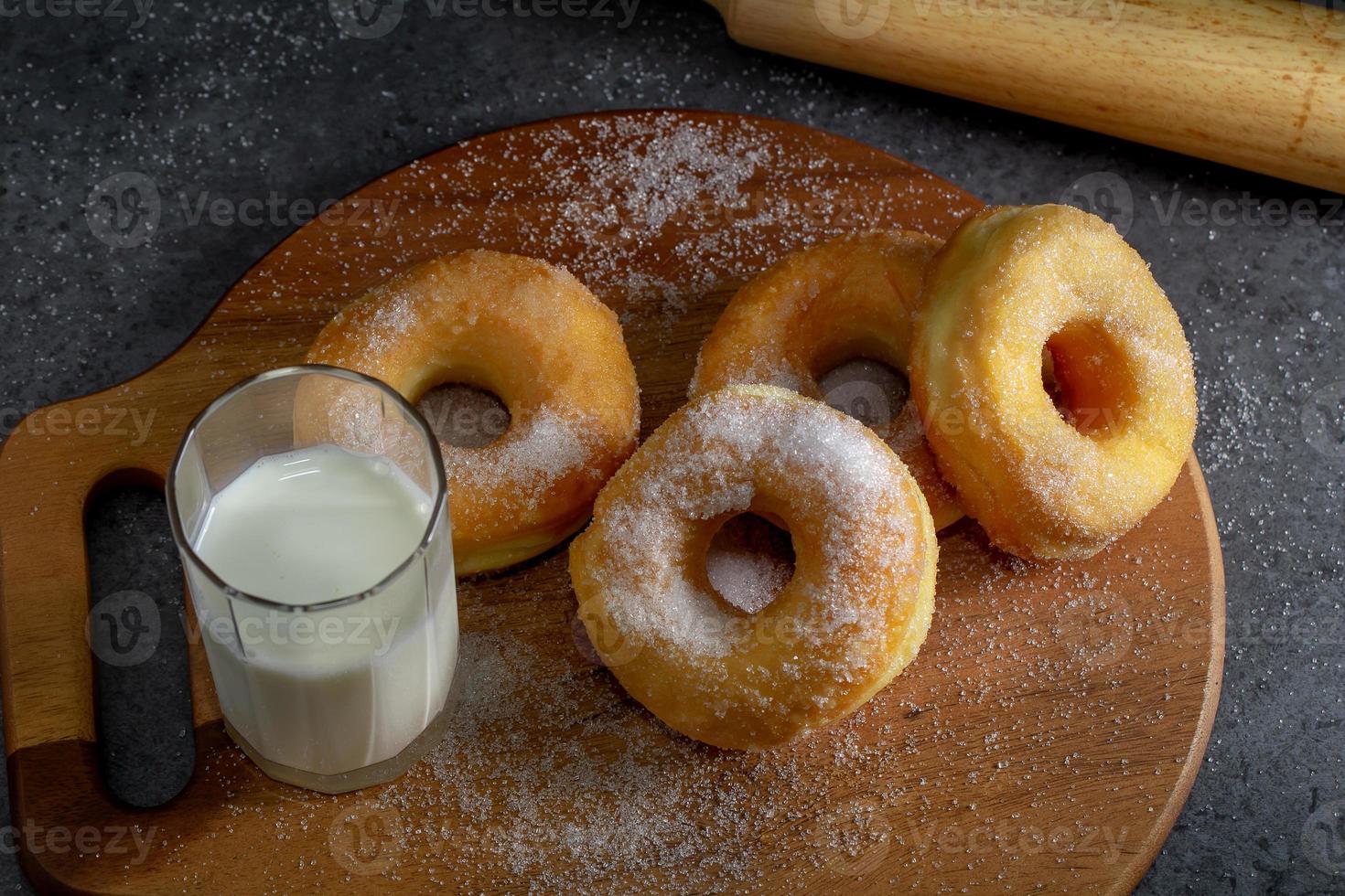 Donuts with sugar on a wooden plate over a dark table background photo