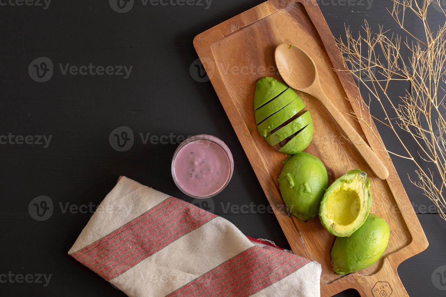 Aguacate orgánico fresco cortado por la mitad sobre una mesa de madera negra foto