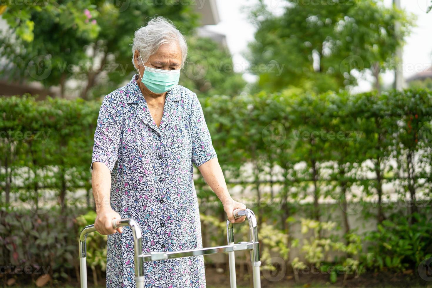 anciana asiática mayor o anciana camina con andador y usa una mascarilla para proteger la infección de seguridad y matar el nuevo virus coronavirus covid-19. foto