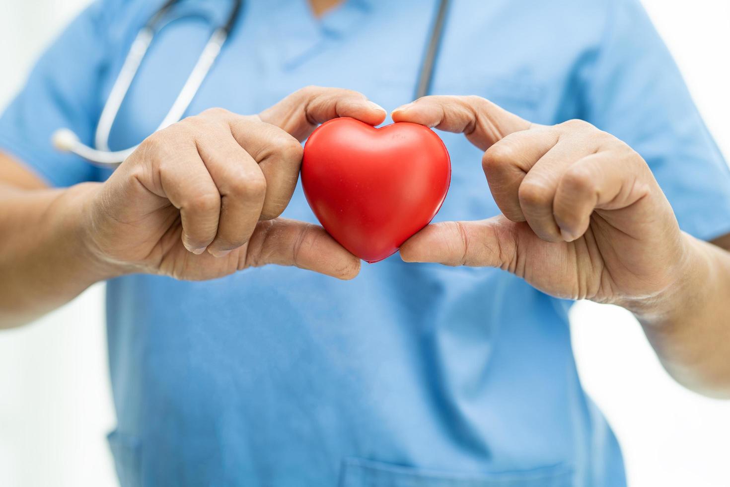 Asian woman doctor holding red heart in nursing hospital ward, healthy strong medical concept photo