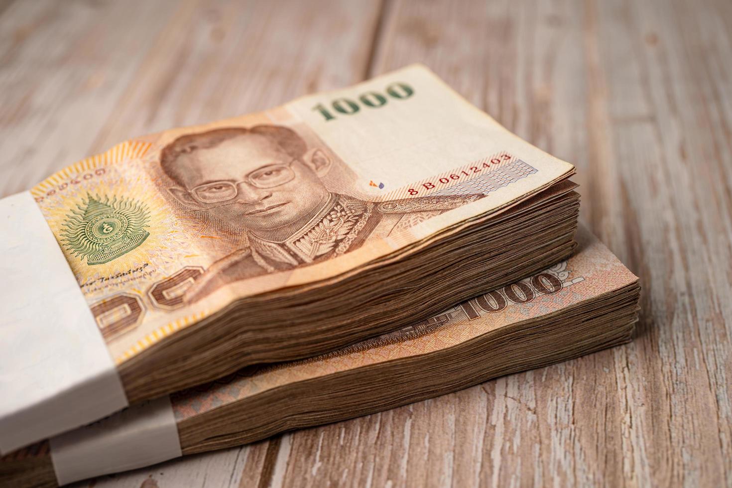Stack of Thai baht banknotes on wooden background, business saving finance investment concept. photo