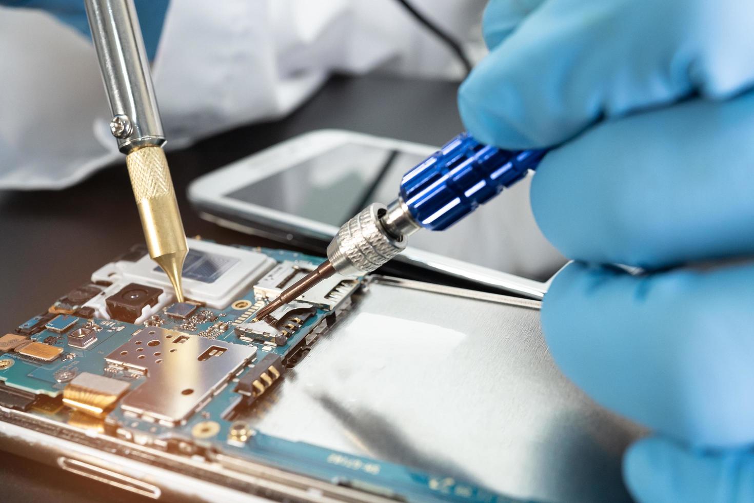 Technician repairing inside of mobile phone by soldering iron. Integrated Circuit. the concept of data, hardware, technology. photo