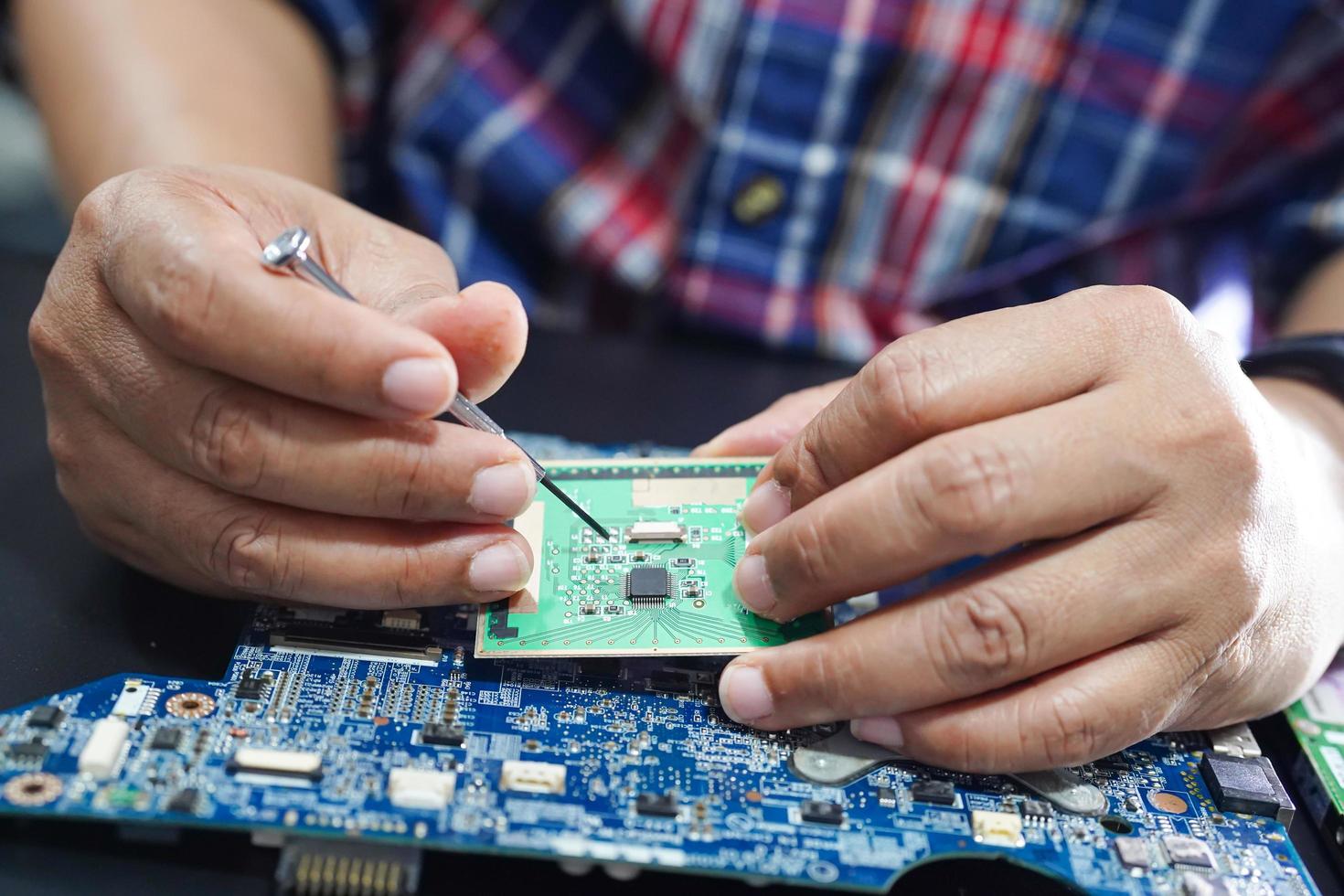 E-waste, technician repairing inside of hard disk by soldering iron. Integrated Circuit. the concept of data, hardware, technician and technology. photo