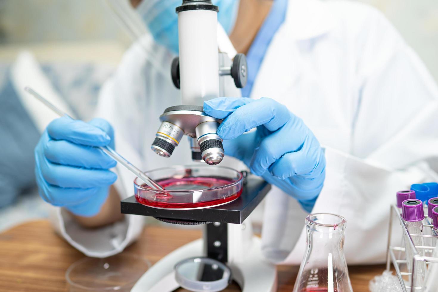 Asian scientist biochemist or microbiologist working research with a microscope in laboratory. For protect outbreak Coronavirus Covid19, bacteria and germs. photo