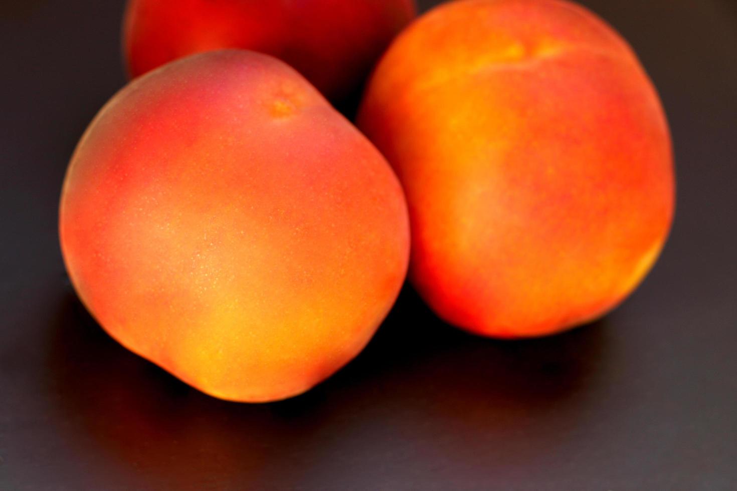 Ripe peach fruit, three peaches Prunus persica close-up on black background photo