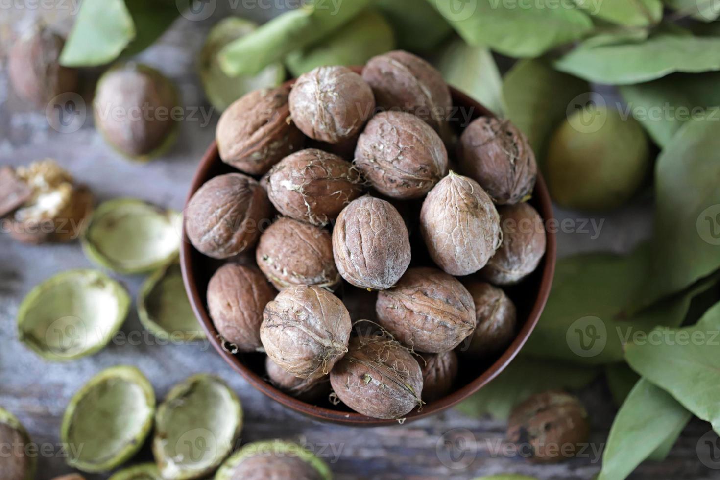 nueces en un bol. hojas de nuez nueces en una cáscara verde foto