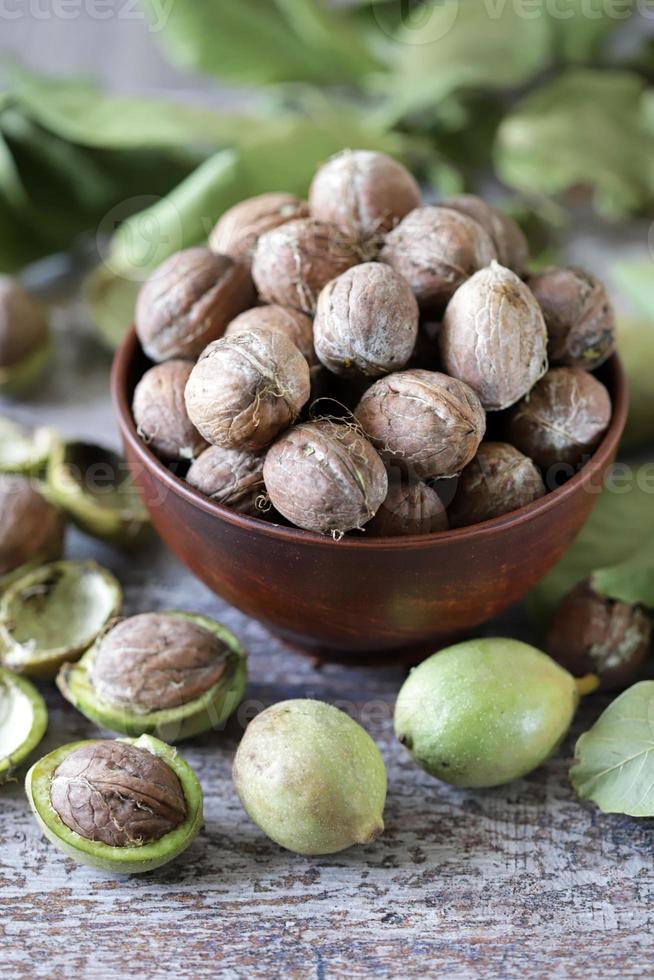 nueces en un bol. hojas de nuez nueces en una cáscara verde foto