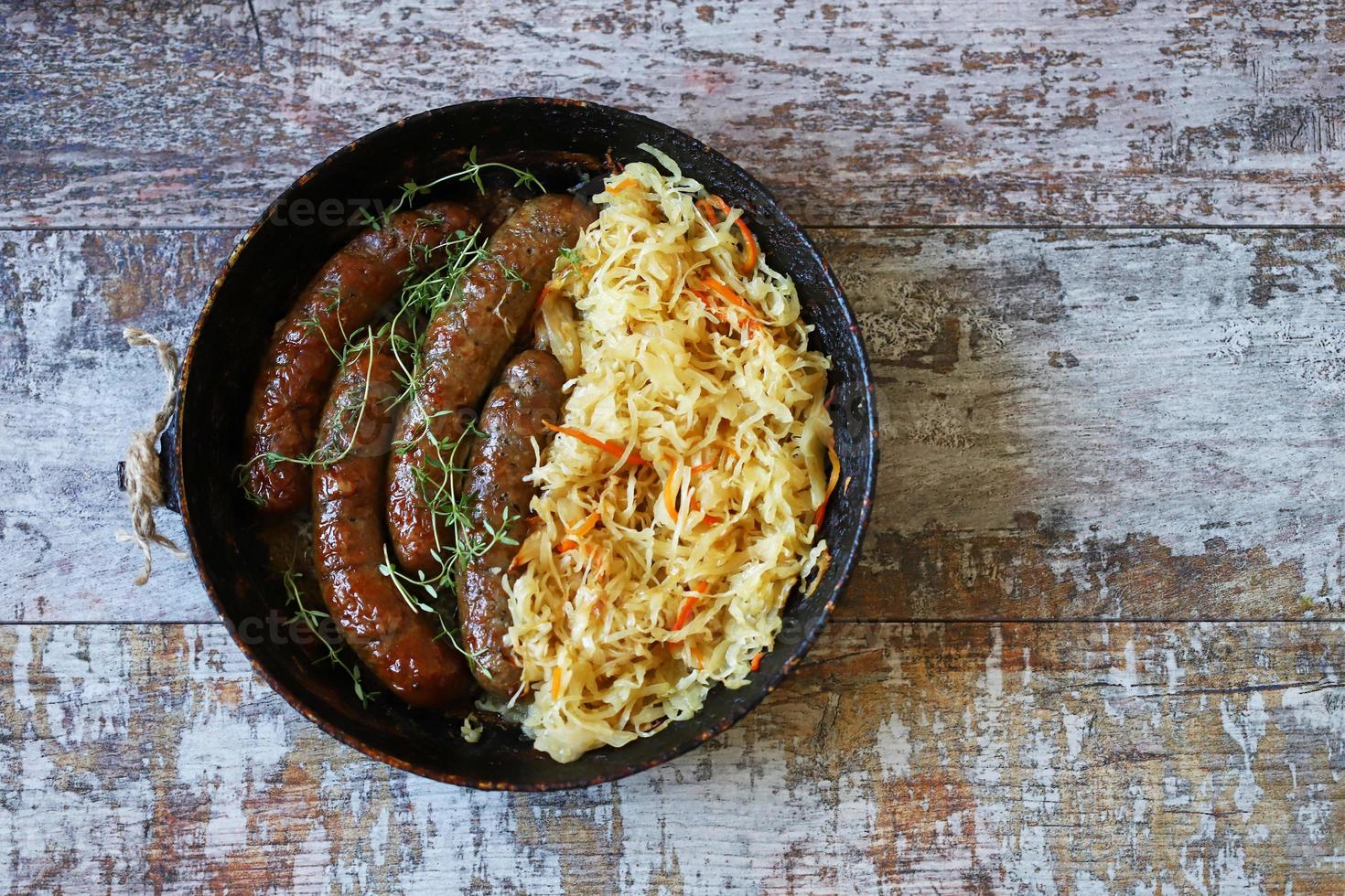 Bavarian sausages in a pan with stewed sauerkraut Oktoberfest food photo