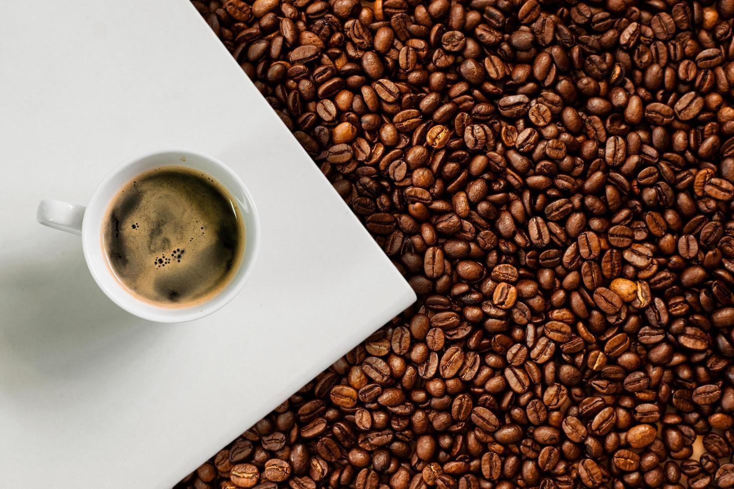 Cup of coffee with coffee beans on table photo