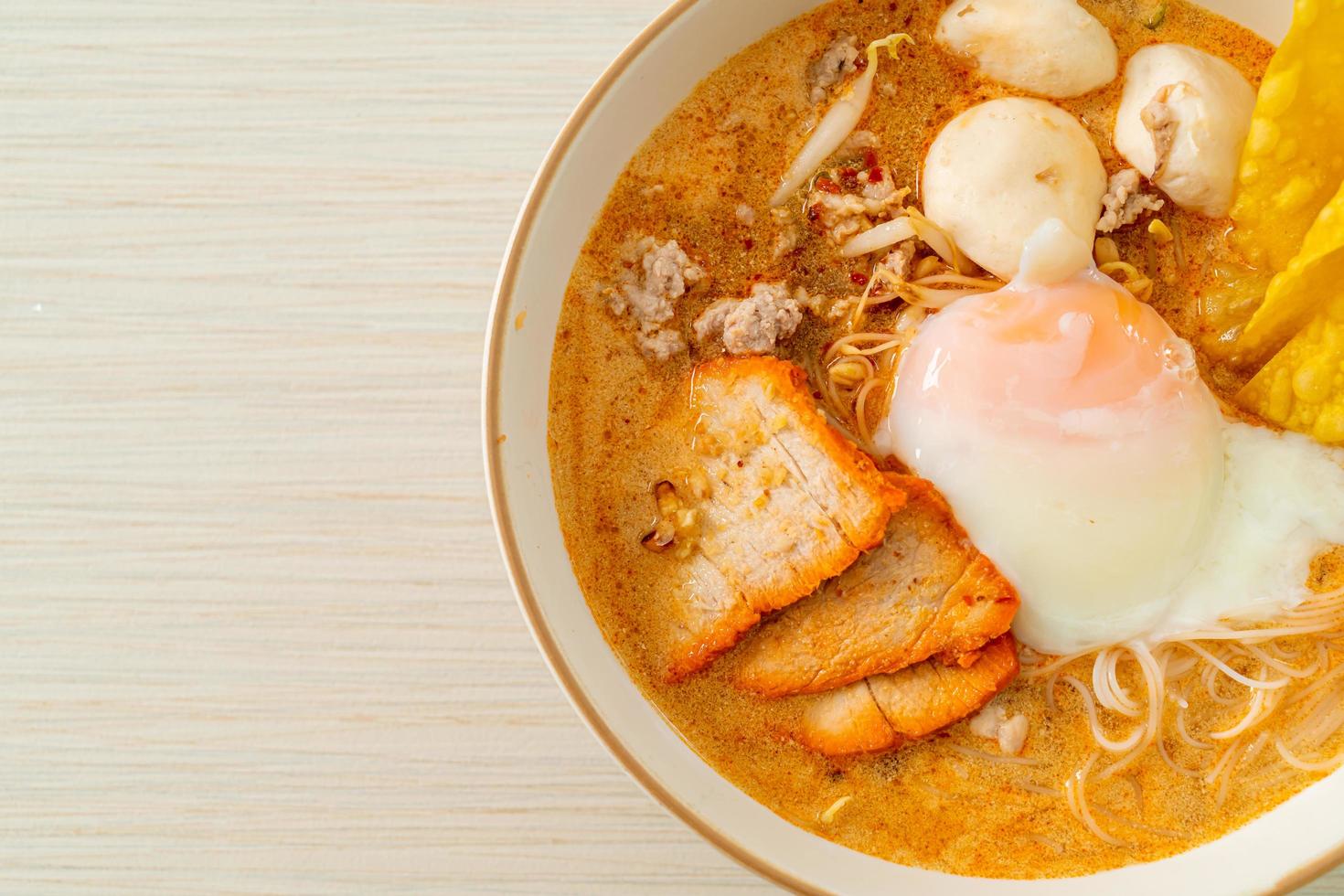 Rice vermicelli noodles with meatball, roasted pork and egg in spicy soup photo