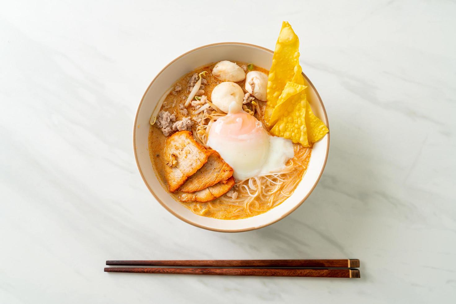 Rice vermicelli noodles with meatball, roasted pork and egg in spicy soup photo