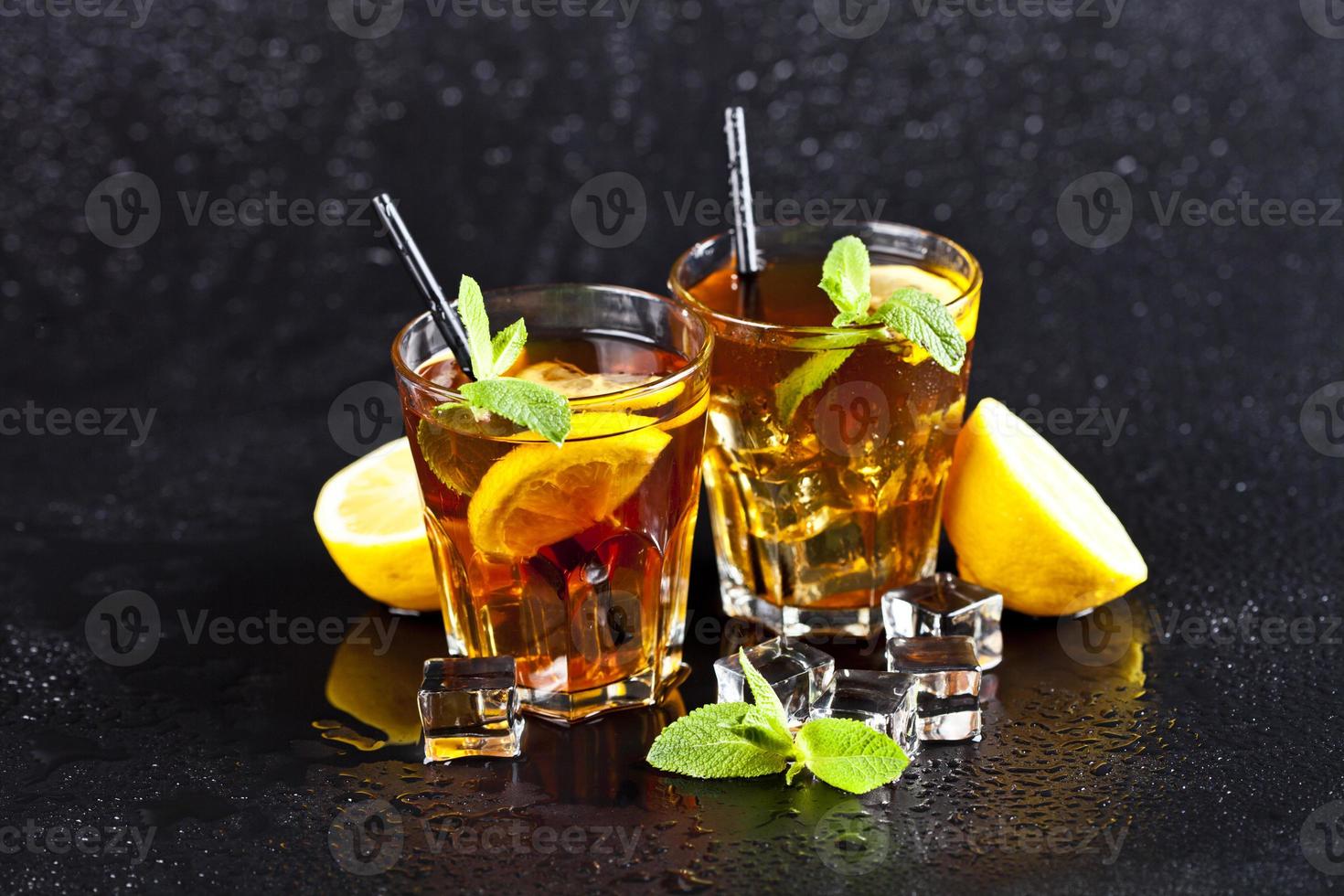 Two glasses with cold traditional iced tea with lemon, mint leaves and ice cubes. photo