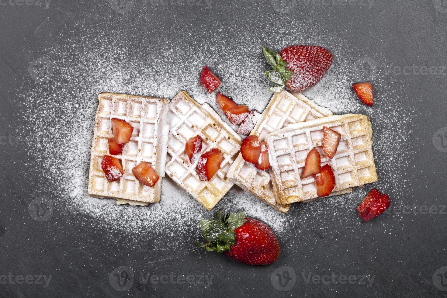 Belgium waffers with strawberries and sugar powder on black board background. photo