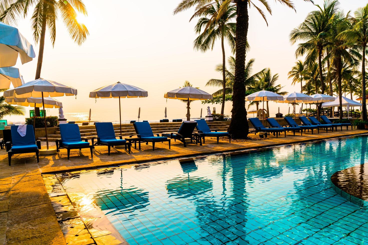 Beautiful umbrella and chair around swimming pool in hotel and resort photo