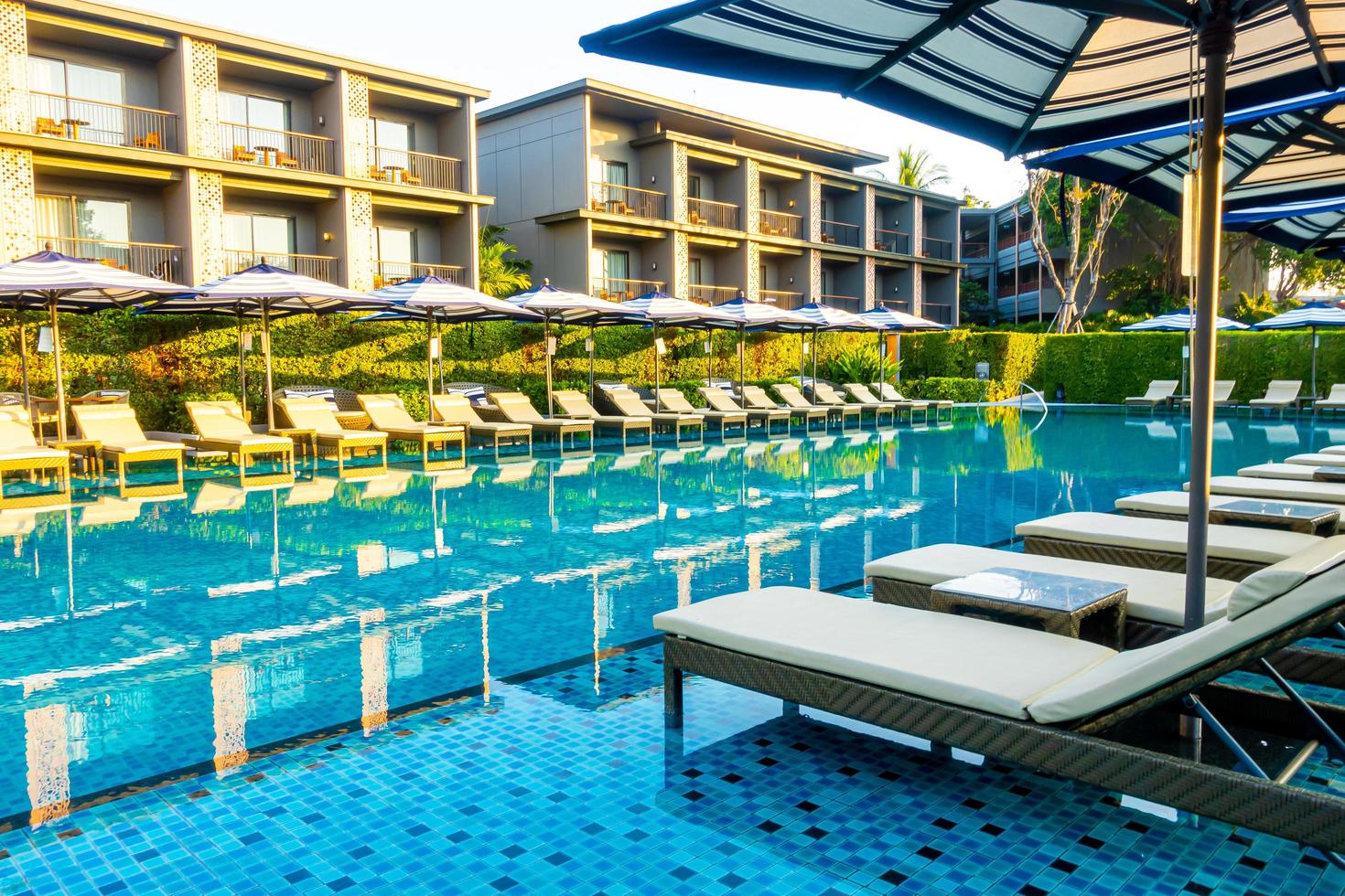 Umbrella and pool bed around outdoor swimming pool in hotel resort for travel holiday vacation photo