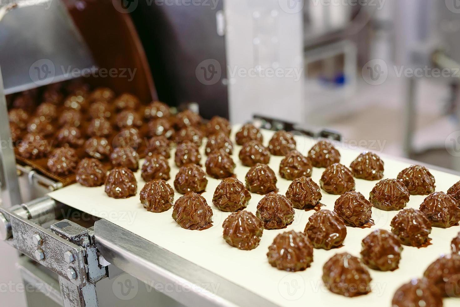 concepto de industria y producción de dulces - procesamiento de caramelos de chocolate en el transportador en la tienda de confitería. foto