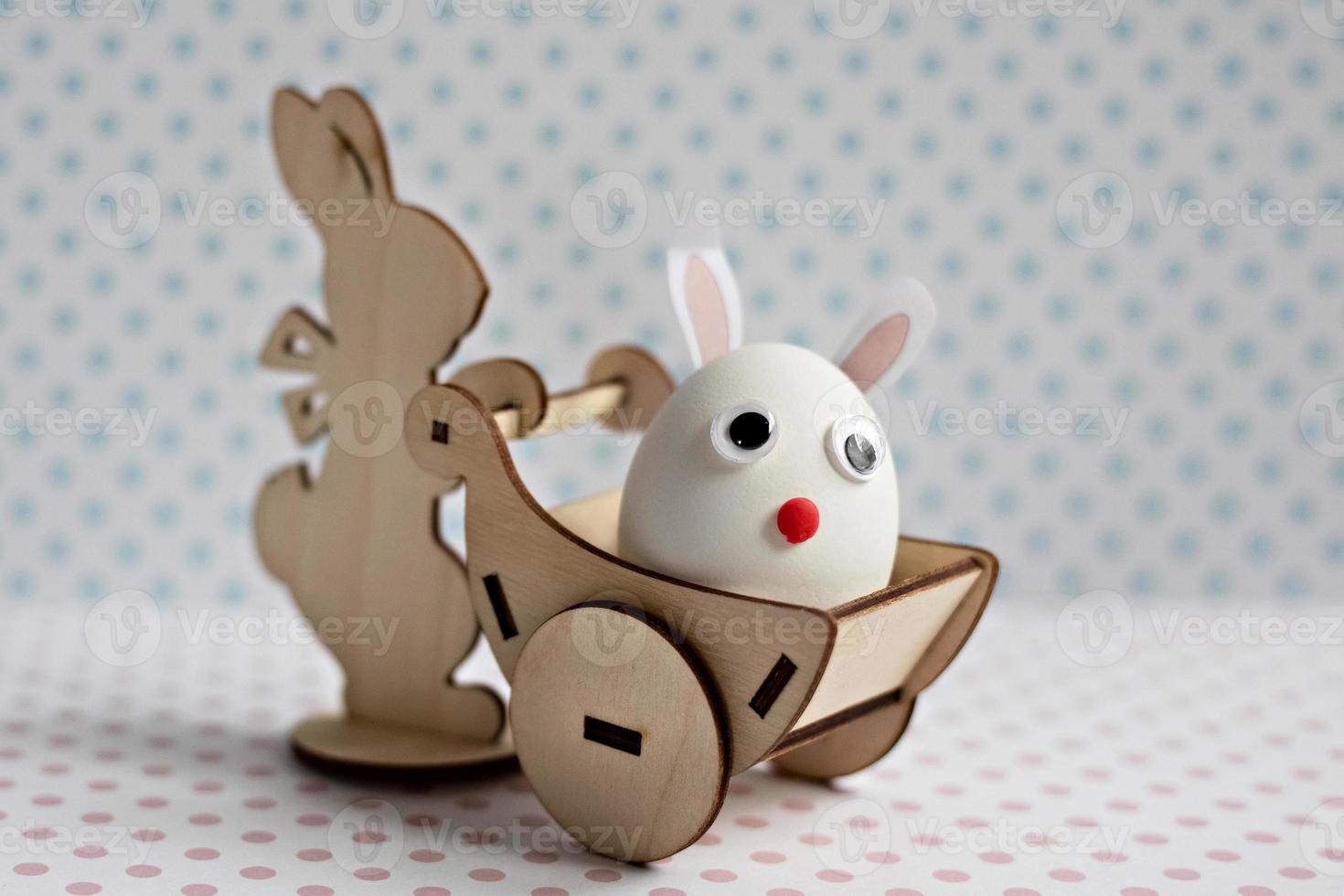 un conejo de madera lleva un carro con un huevo con orejas de conejo. decoraciones de pascua foto