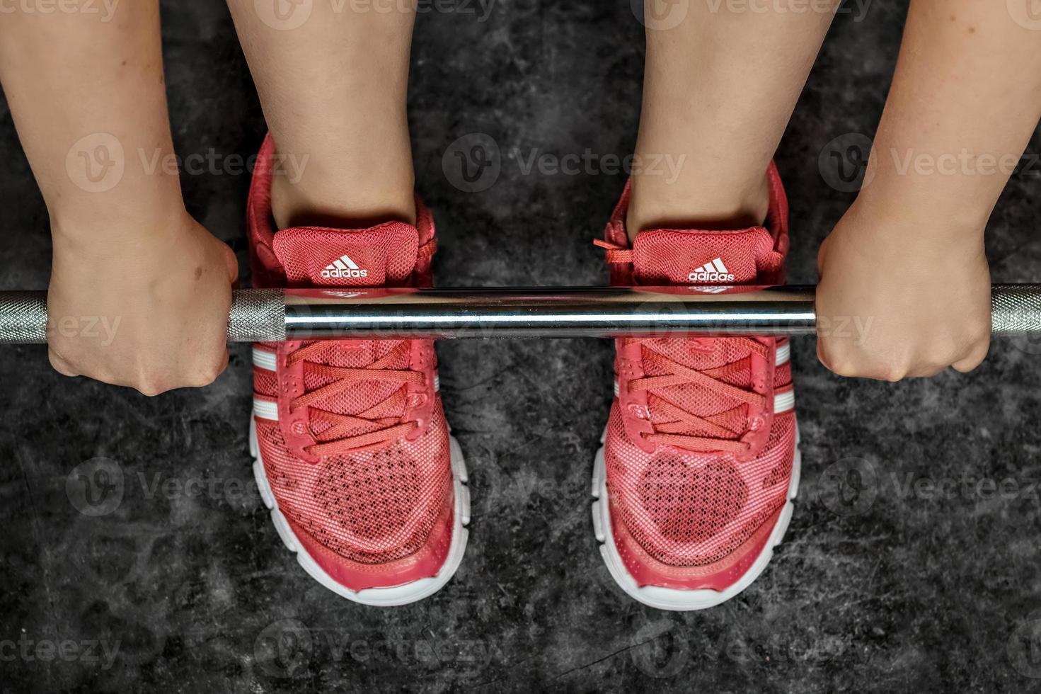 piernas de una niña en zapatillas de deporte en el bar del gimnasio. estilo de vida saludable, deportes. foto