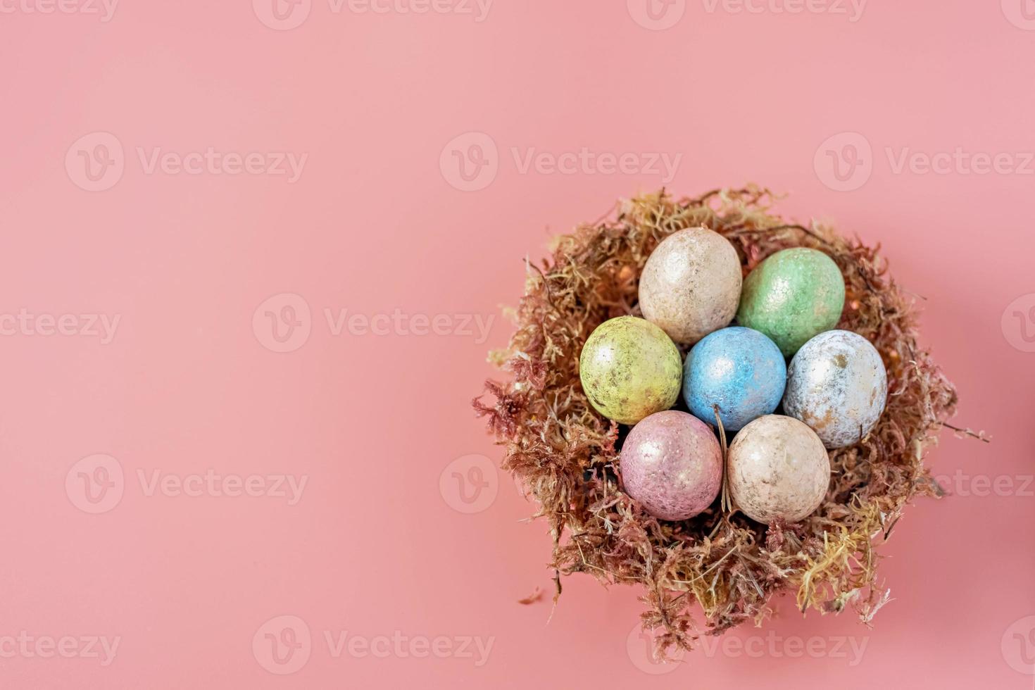 huevos de pascua en un nido natural con musgo sobre un fondo rosa. vista desde arriba foto