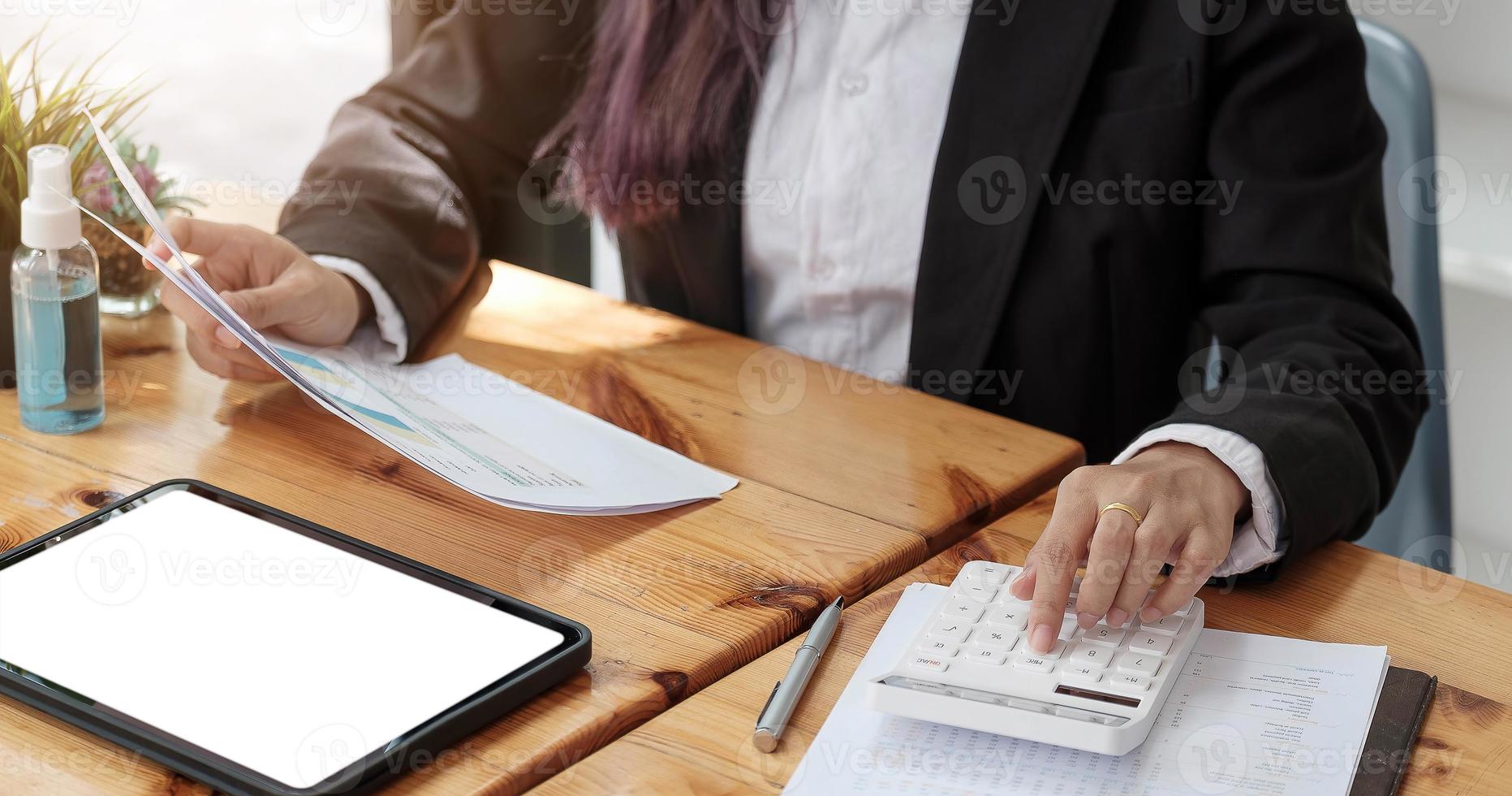 mujer con informe financiero y calculadora. Mujer con calculadora para calcular el informe en la mesa en la oficina foto