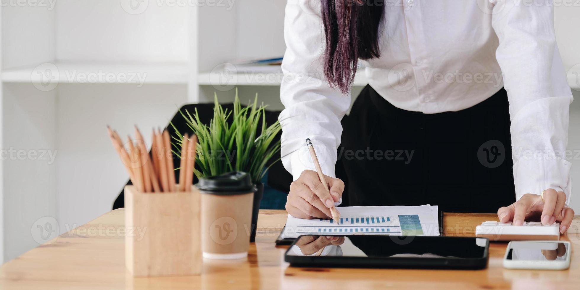 Woman with financial report and calculator. Woman using calculator to calculate report at the table in office photo