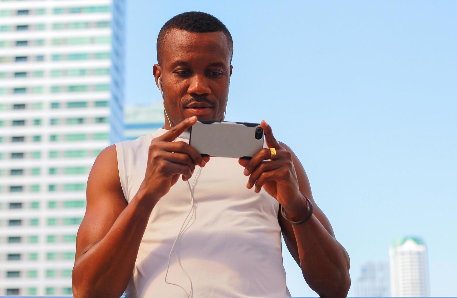 Hombres guapos en ropa deportiva relajándose del ejercicio al aire libre escuchando música desde un teléfono inteligente o teléfono móvil conceptos de ejercicio saludable foto