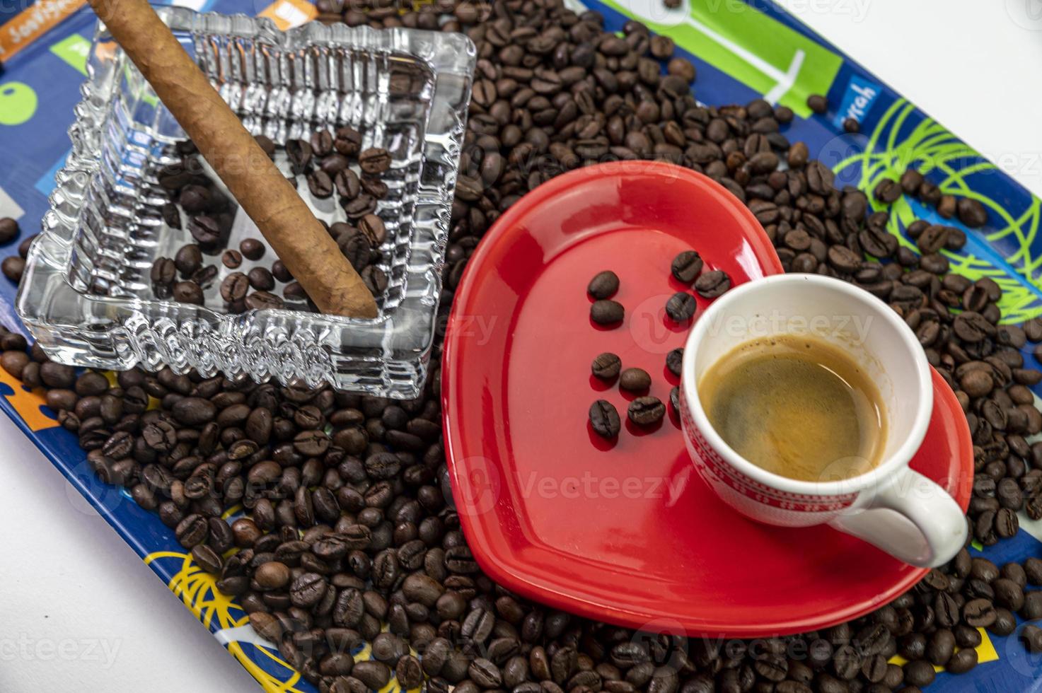 Composición de granos de café con taza y platillo en forma de corazón foto