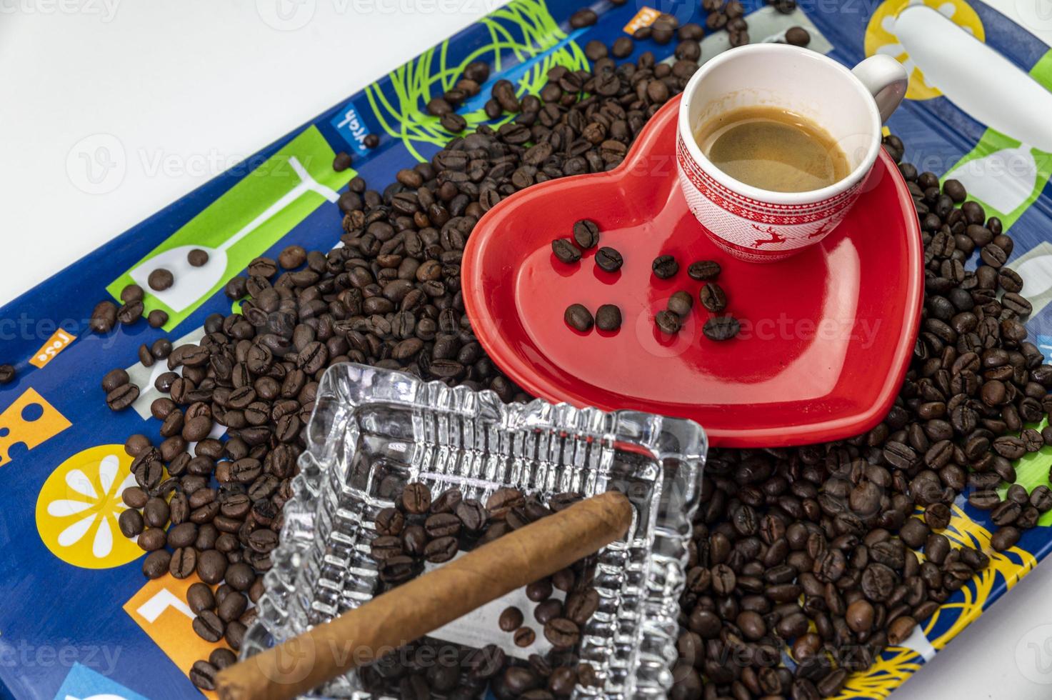 Composición de granos de café con taza y platillo en forma de corazón foto