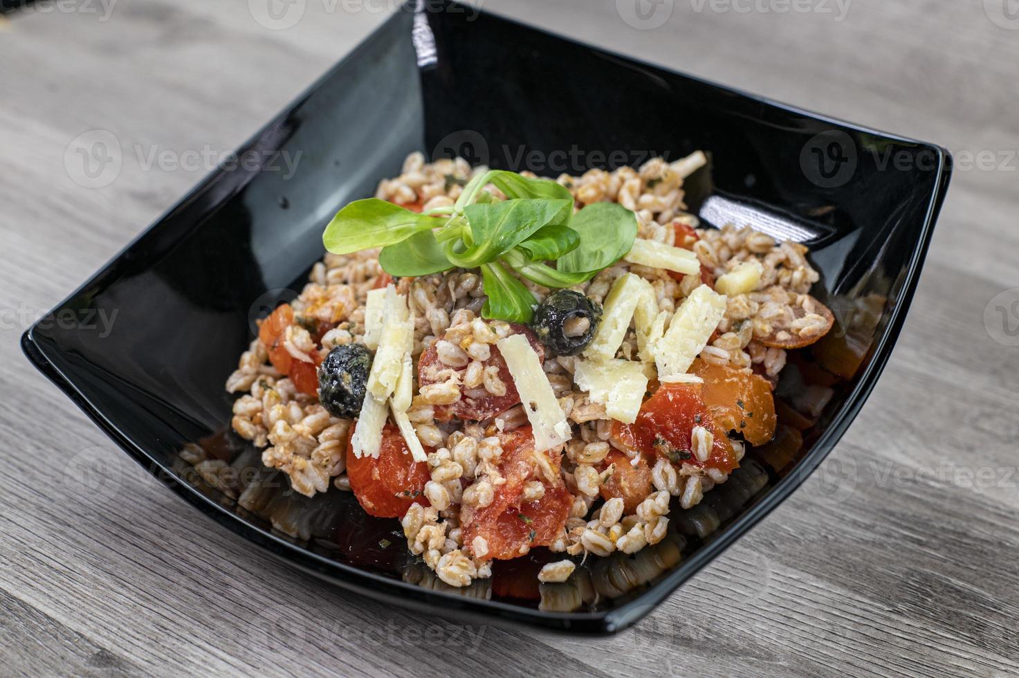servido en un plato negro de ensalada de espelta foto