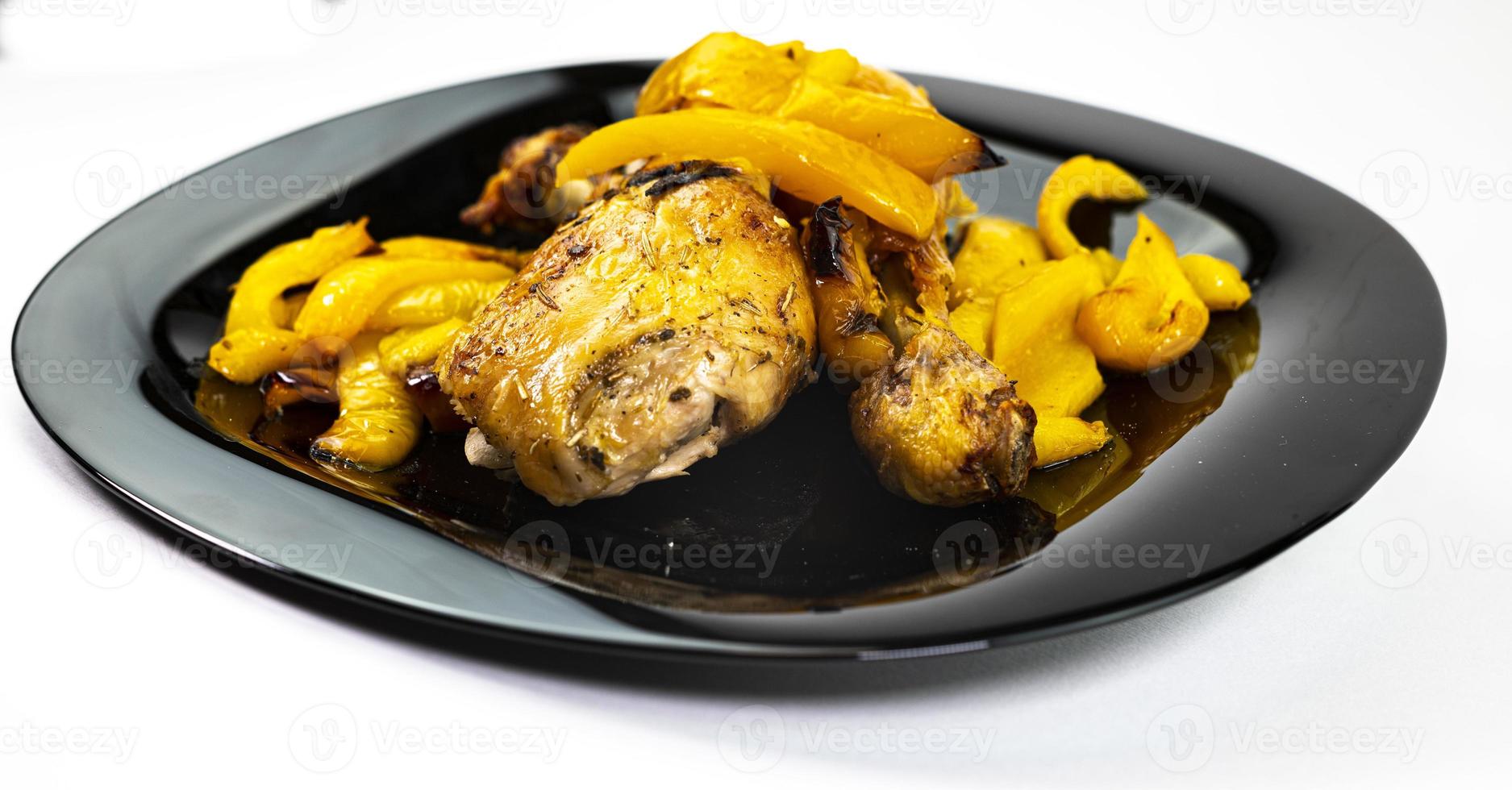 así de pollo con pimientos amarillos en un plato negro foto