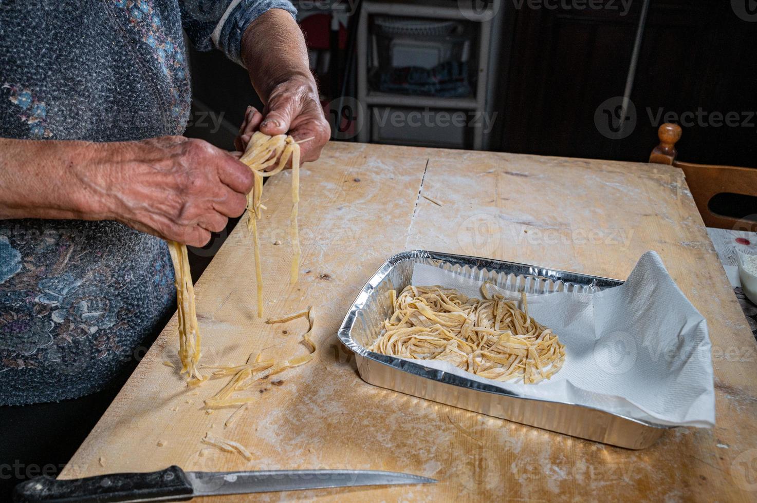 la abuela arregla los fideos en la plantilla de aluminio foto