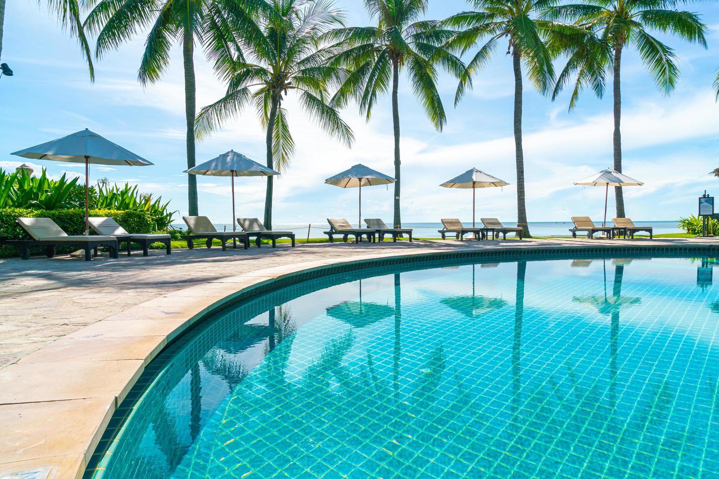 Beautiful umbrella and chair around swimming pool in hotel and resort photo