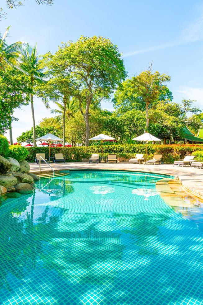 Beautiful umbrella and chair around swimming pool in hotel and resort photo