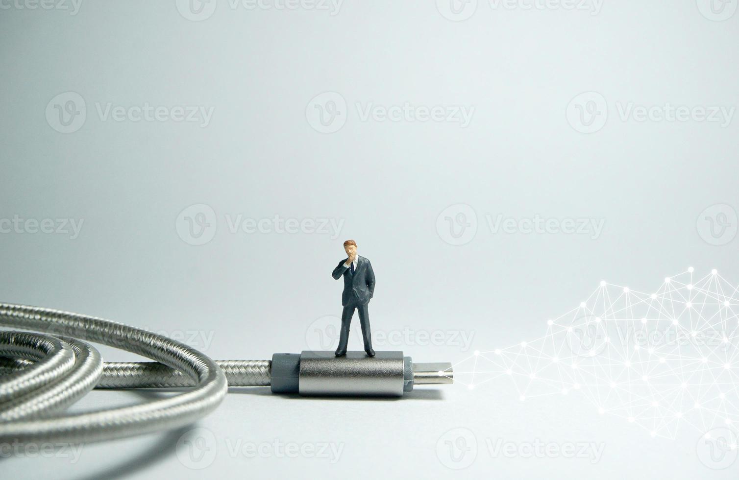 Businessman figure standing on usb USB type C cable. E commerce concept. photo