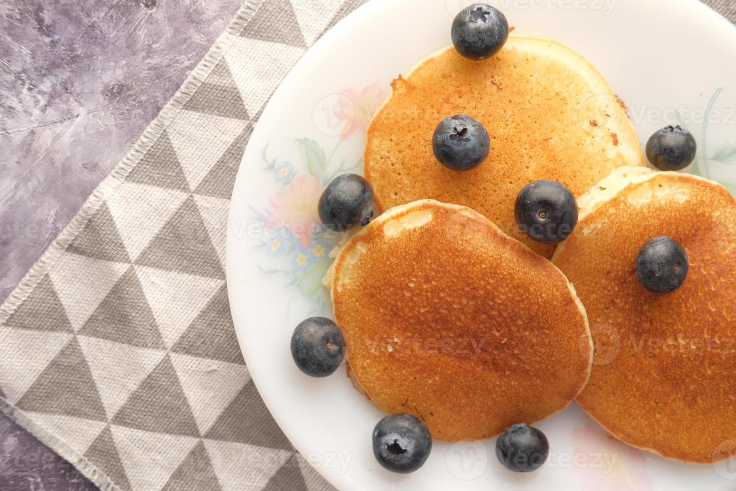 Comida sabrosa con bayas y pan cake en un tazón sobre fondo negro foto