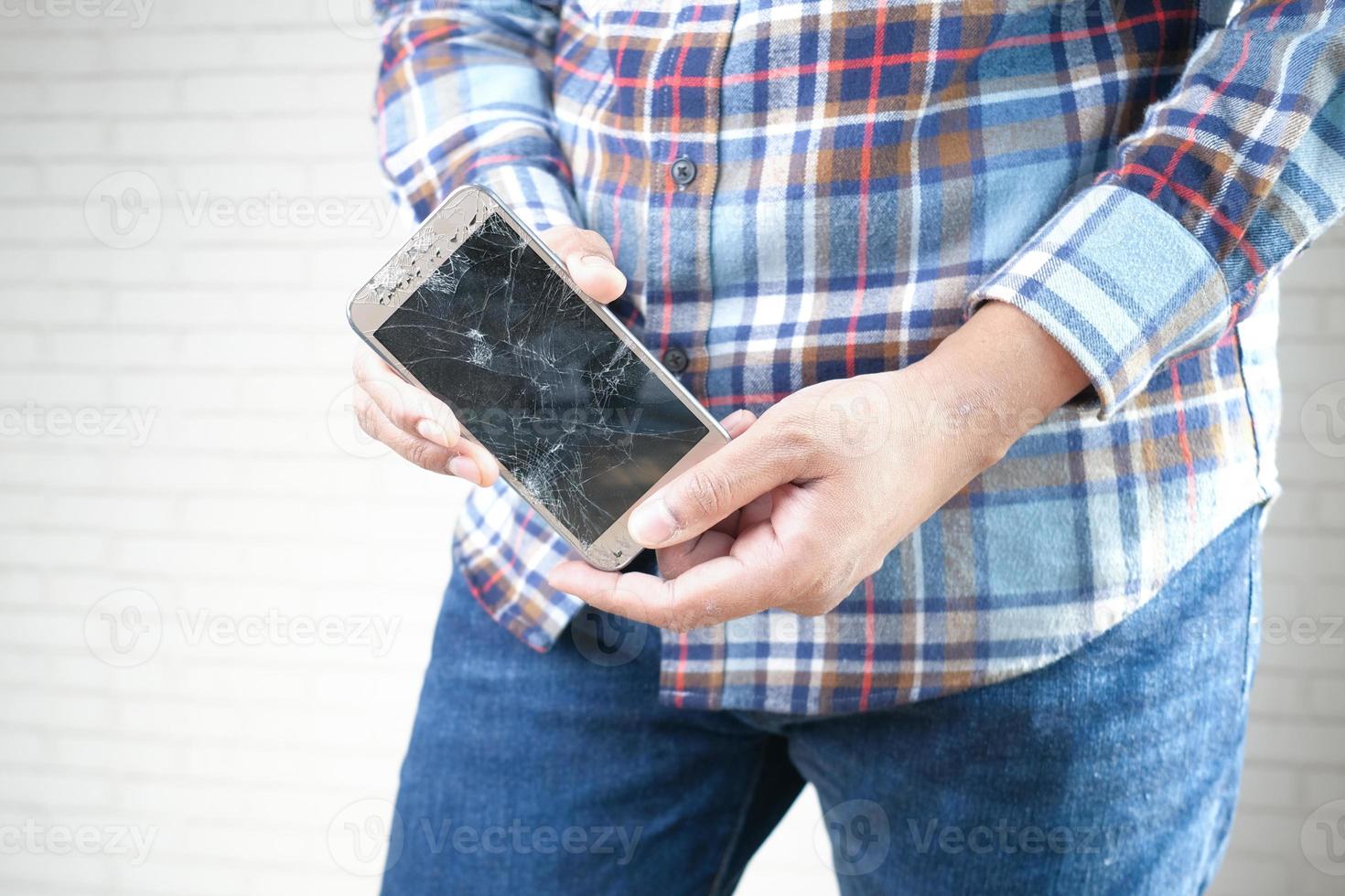 Cerca de la mano del hombre sosteniendo un teléfono inteligente roto. foto