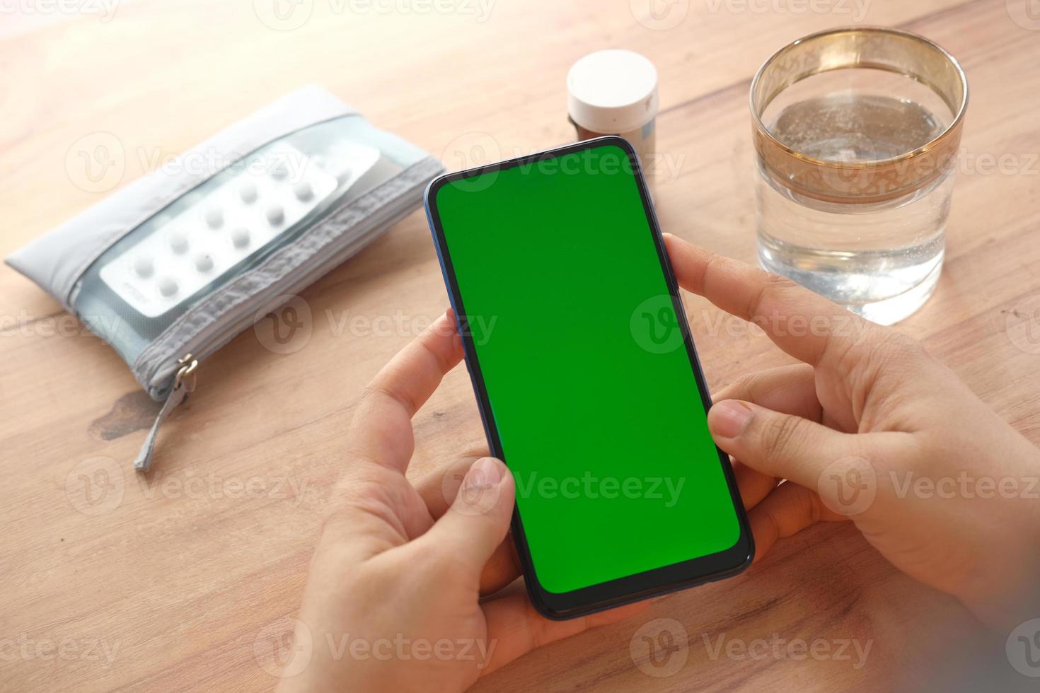 Cerca de la mano de la mujer con teléfonos inteligentes y píldoras médicas en la mesa foto