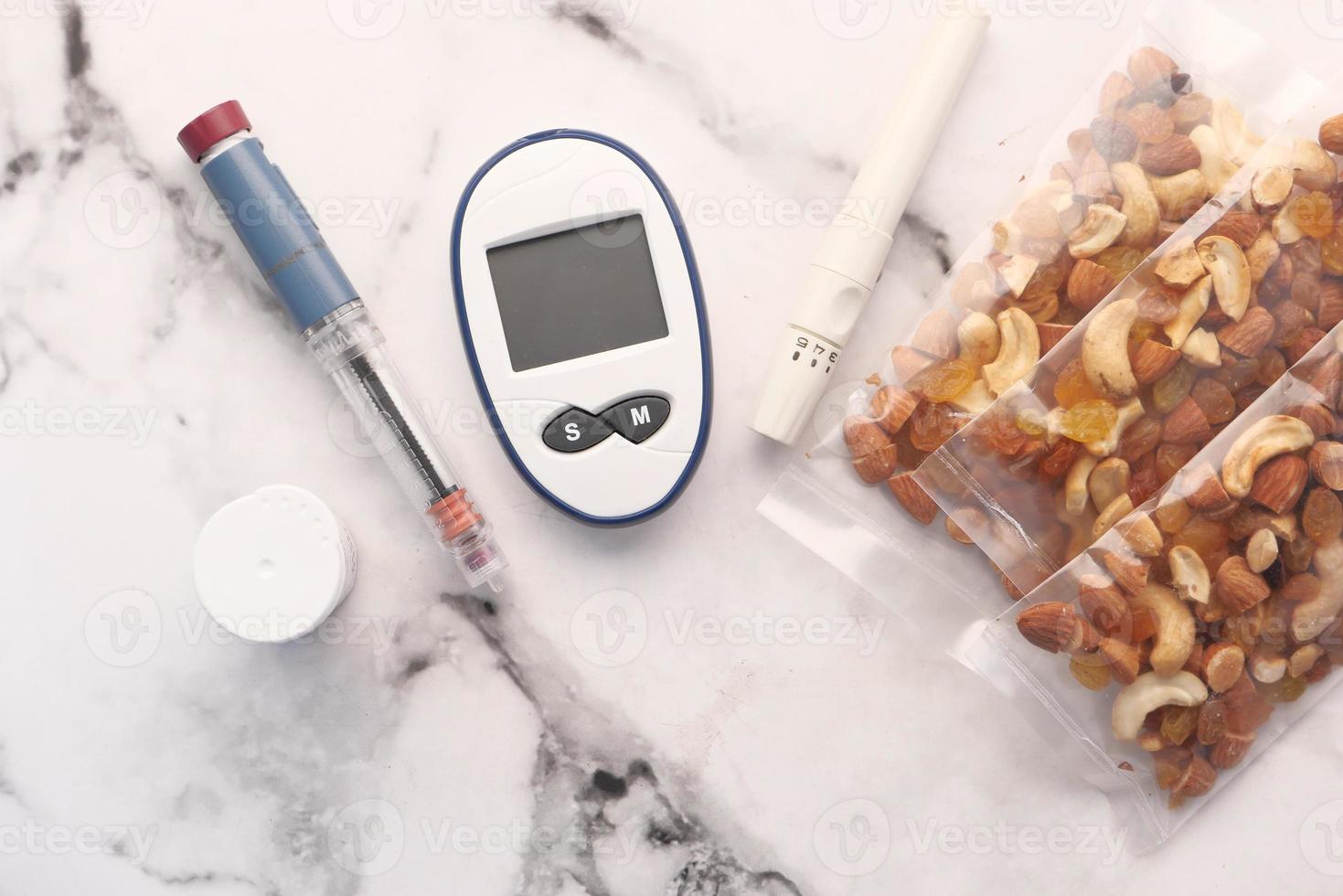 Close up of diabetic measurement tools, insulin and mixed nut on table