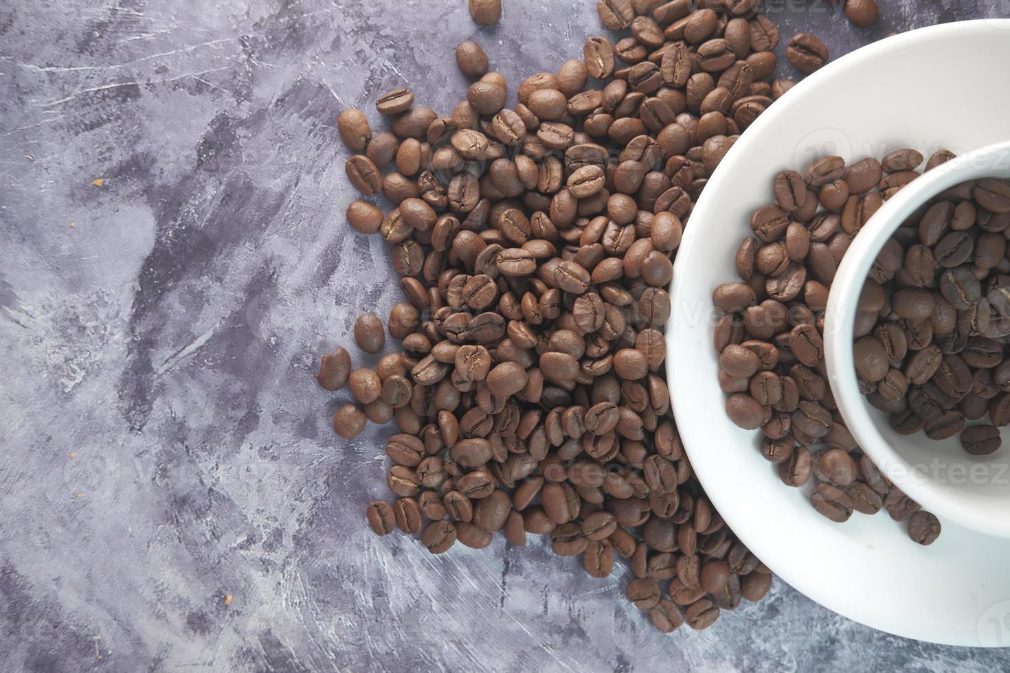 Cerca de los granos de café frescos en una taza sobre fondo negro con espacio de copia. foto