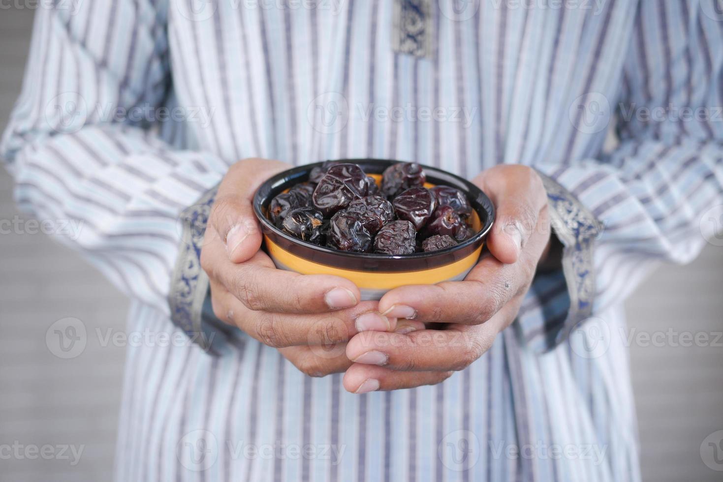 concepto de ramadán, mano sosteniendo un plato de frutas de dátiles foto