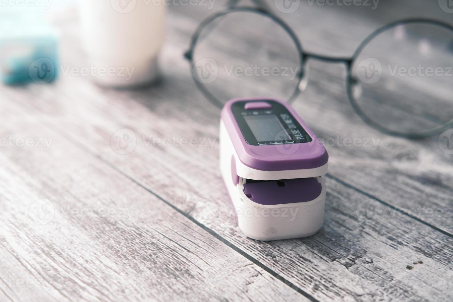 Close up of pulse oximeter and a eye glass on table photo