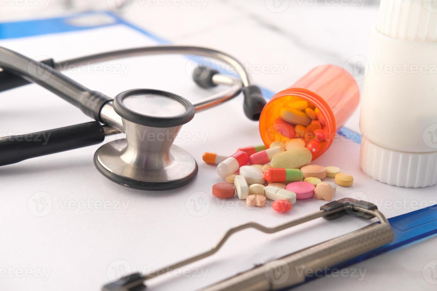 Thermometer , stethoscope and pills container on pink background photo