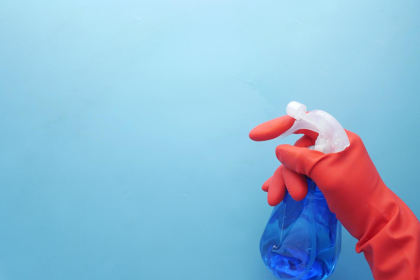 Hand in red rubber gloves holding spray bottle with copy space photo