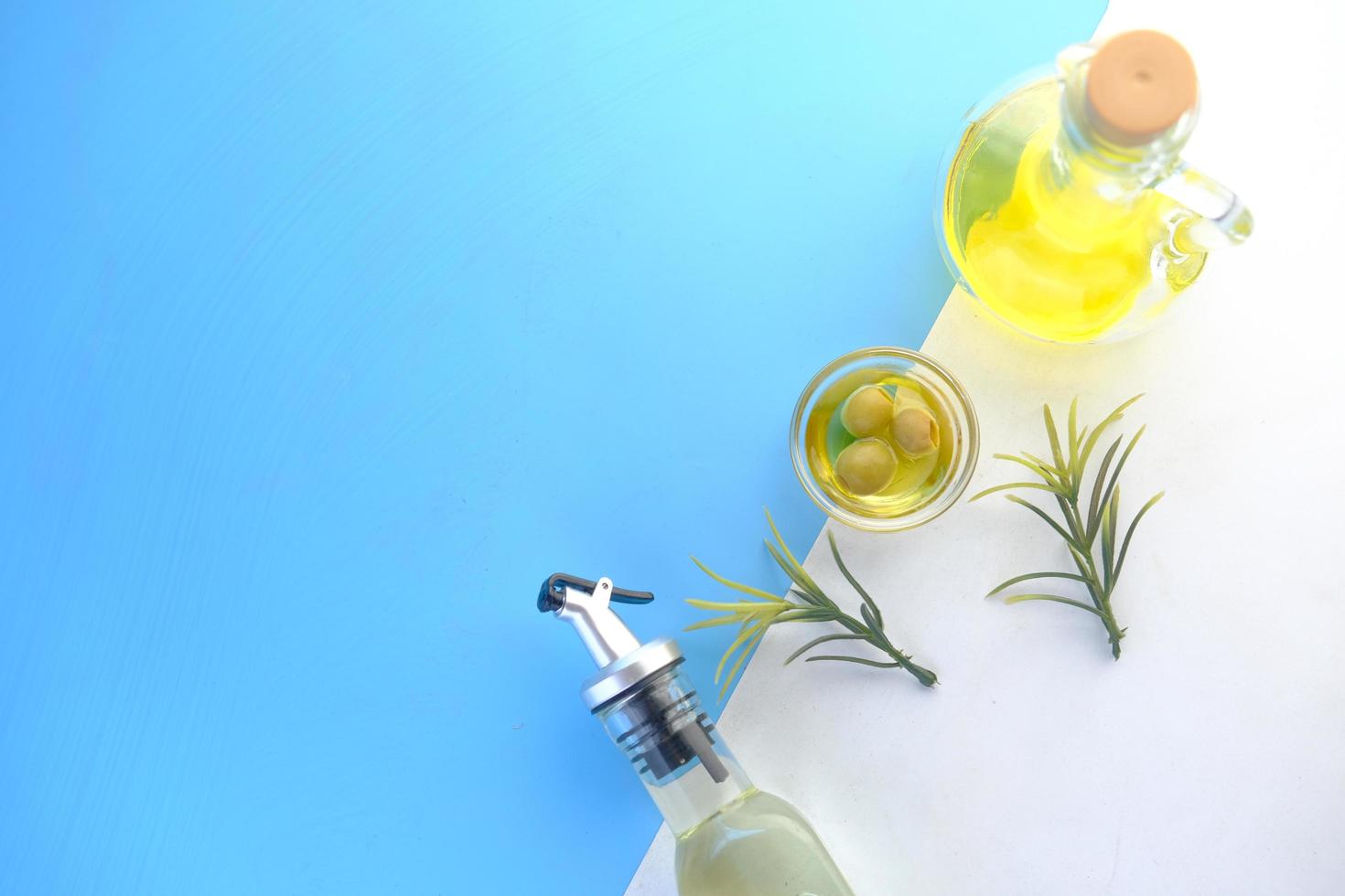 Botella de aceite de oliva y aceitunas frescas en un recipiente sobre fondo de color foto