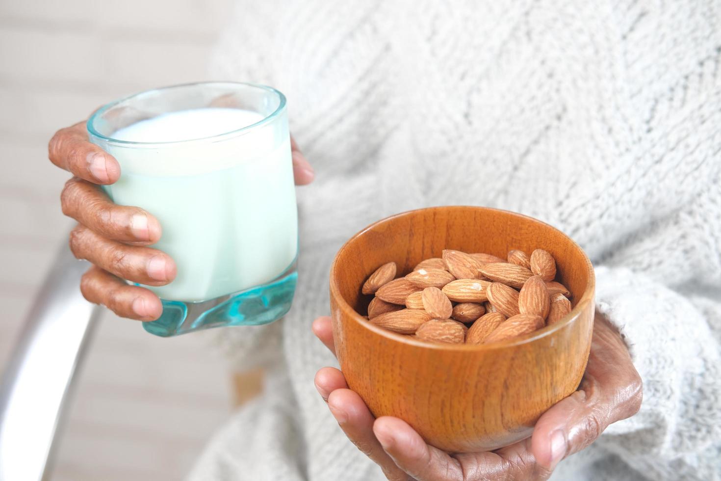 Close up senior women hand holding a bowl on almond and glass of milk photo