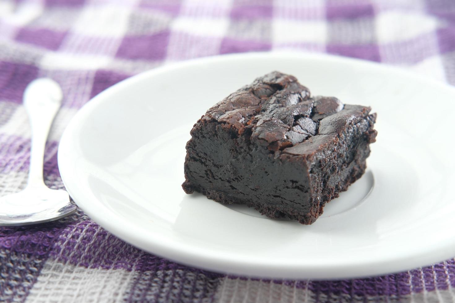 Slice of homemade brownie on plate on table photo